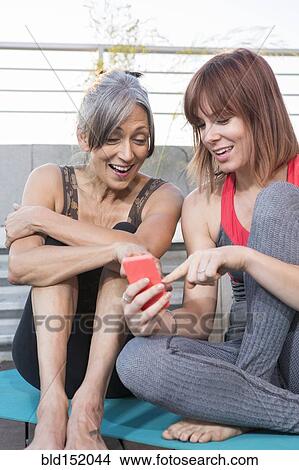 Picture - Women using cell phone on exercise mat. Fotosearch