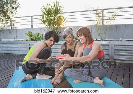 Women using cell phone on exercise mat View Large Photo Image Stock Photo - Women using cell phone on exercise mat. Fotosearch