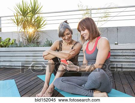 Women using cell phone on exercise mat View Large Photo Image Stock Photography - Women using cell phone on exercise mat. Fotosearch