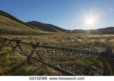 Stock Photo - Wooden fence and rural field under blue sky. Fotosearch