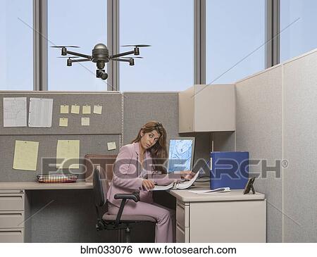 Stock Photograph - Drone hovering over Hispanic businesswoman in office. Fotosearch