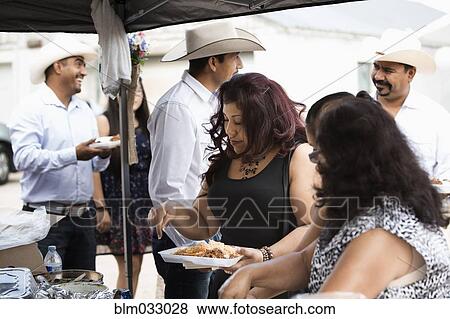 Stock Photo - Hispanic community eating at quinceanera. Fotosearch