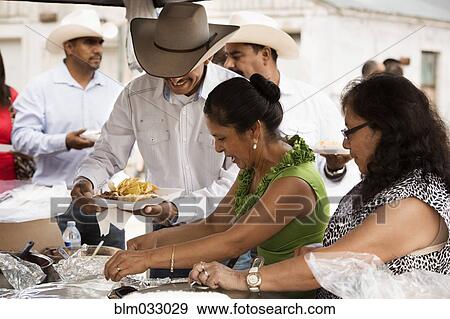 Stock Photo - Hispanic community eating at quinceanera. Fotosearch