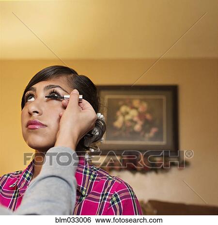Stock Photograph - Hispanic girl having makeup applied in living room. Fotosearch