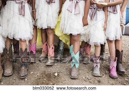 Stock Image - Hispanic girls wearing cowboy boots at quinceanera. Fotosearch