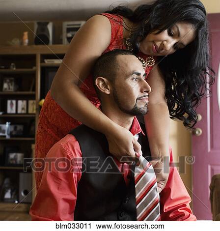 Stock Image - Hispanic woman adjusting tie for husband. Fotosearch