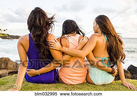 Stock Photography - Pacific Islander women hugging near beach. Fotosearch
