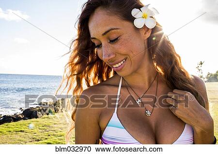 Stock Image - Smiling woman wearing flower in her hair near ocean. Fotosearch