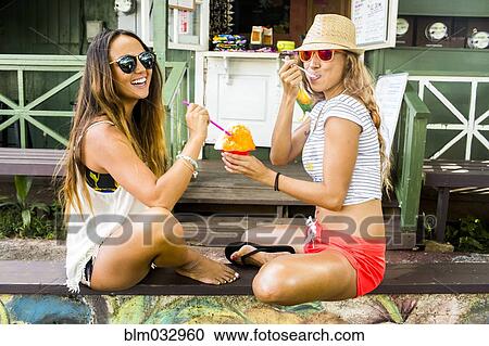 Stock Image - Smiling women sharing shaved ice. Fotosearch