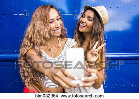Picture - Women taking cell phone photograph together. Fotosearch