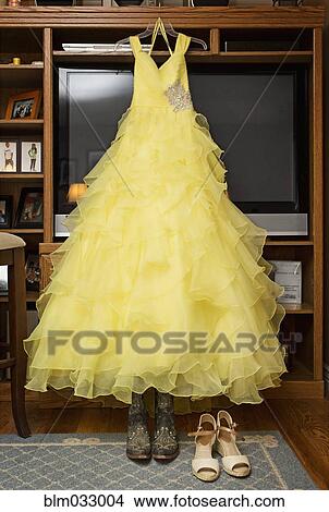Picture - Yellow quinceanera dress hanging in living room. Fotosearch