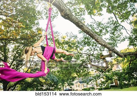 Acrobatic Caucasian girl hanging on fabric under tree View Large Photo Image Picture - Acrobatic Caucasian girl hanging on fabric under tree. Fotosearch