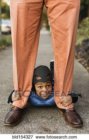 Stock Photo - African American boy trick-or-treating with father on Halloween. Fotosearch