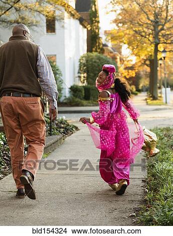 African American girl trick-or-treating with father on Halloween View Large Photo Image Picture - African American girl trick-or-treating with father on Halloween. Fotosearch