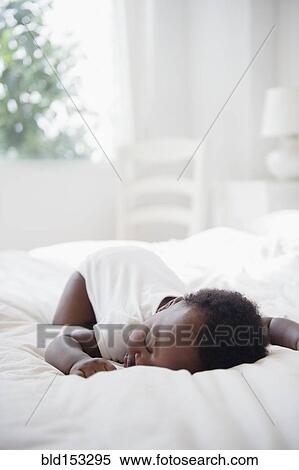 Stock Photography - Black baby sleeping on bed. Fotosearch