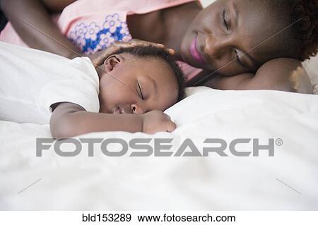 Black mother admiring sleeping son on bed View Large Photo Image Stock Photo - Black mother admiring sleeping son on bed. Fotosearch