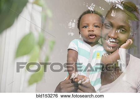 Stock Photograph - Black mother and son looking out window. Fotosearch
