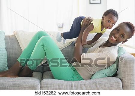 Stock Image - Black mother and son playing on sofa. Fotosearch