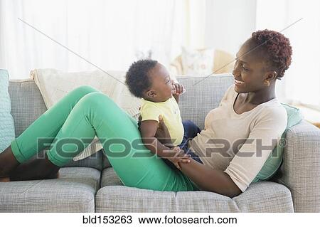 Stock Image - Black mother and son playing on sofa. Fotosearch