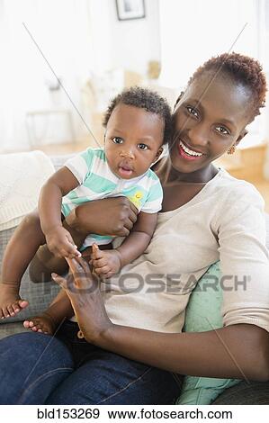 Stock Photo - Black mother and son playing on sofa. Fotosearch