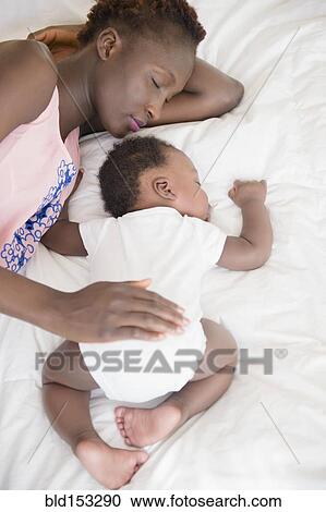 Stock Image - Black mother and son sleeping on bed. Fotosearch