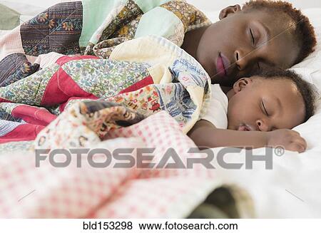 Stock Photo - Black mother and son sleeping on bed. Fotosearch