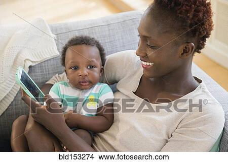 Black mother and son using cell phone on sofa View Large Photo Image Picture - Black mother and son using cell phone on sofa. Fotosearch