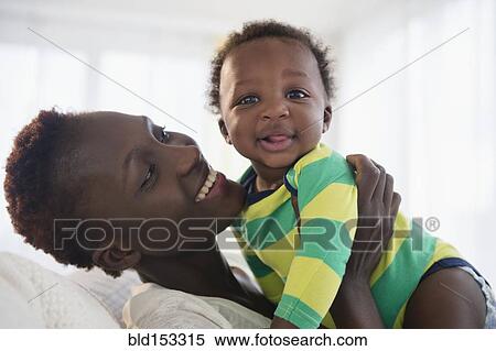 Stock Photography - Black mother holding baby boy. Fotosearch