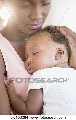 Picture - Black mother holding sleeping son. Fotosearch