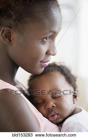 Stock Image - Black mother holding sleeping son. Fotosearch