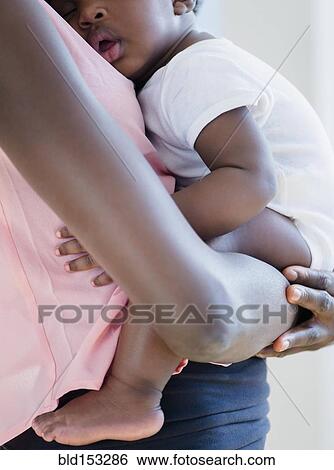 Stock Photograph - Black mother holding sleeping son. Fotosearch