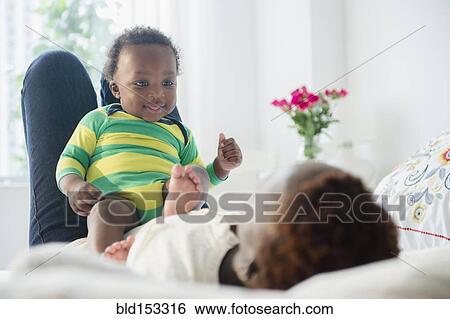 Black mother playing with baby boy on bed View Large Photo Image Stock Photograph - Black mother playing with baby boy on bed. Fotosearch