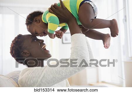 Picture - Black mother playing with baby boy. Fotosearch