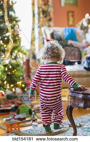 Stock Image - Caucasian baby boy playing with toys near Christmas tree. Fotosearch