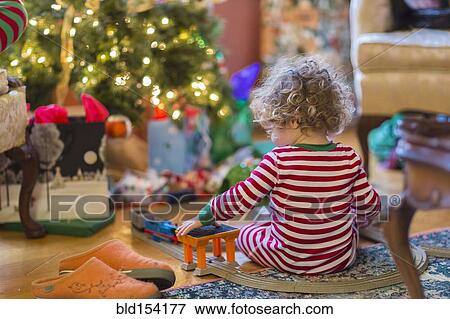 Caucasian baby boy playing with toys near Christmas tree View Large Photo Image Stock Photo - Caucasian baby boy playing with toys near Christmas tree. Fotosearch