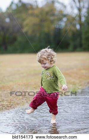 Caucasian baby boy splashing in puddle View Large Photo Image Stock Image - Caucasian baby boy splashing in puddle. Fotosearch