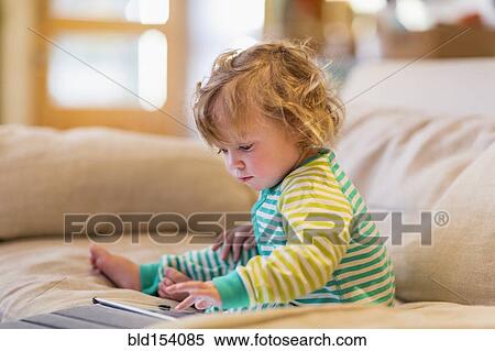 Stock Photography - Caucasian baby boy using digital tablet on sofa. Fotosearch