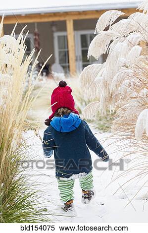 Stock Photography - Caucasian baby boy walking in snowy garden. Fotosearch