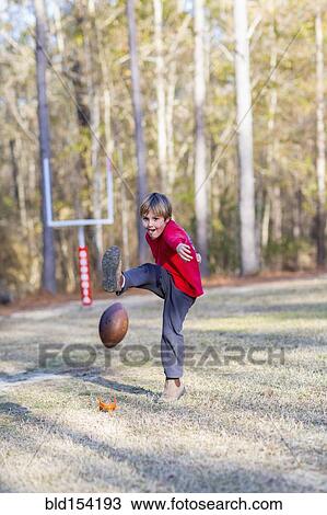 Caucasian boy kicking football in field View Large Photo Image Stock Image - Caucasian boy kicking football in field. Fotosearch