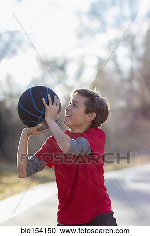Stock Image - Caucasian boy playing basketball on court. Fotosearch