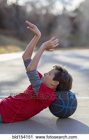 Stock Image - Caucasian boy playing basketball on court. Fotosearch