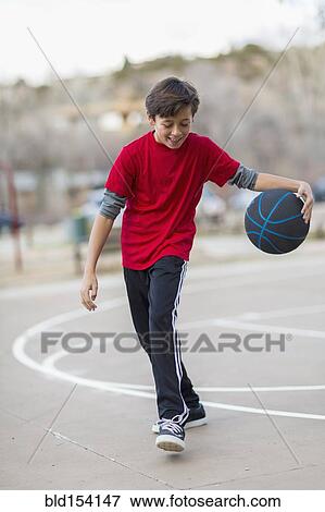 Stock Photo - Caucasian boy playing basketball on court. Fotosearch