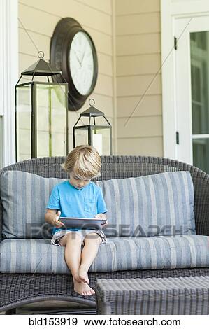 Stock Photo - Caucasian boy using digital tablet on sofa. Fotosearch
