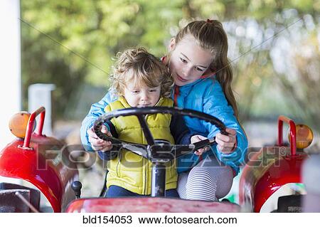 Stock Image - Caucasian brother and sister driving tractor. Fotosearch