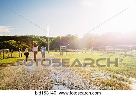Stock Image - Caucasian children walking on dirt road on ranch. Fotosearch