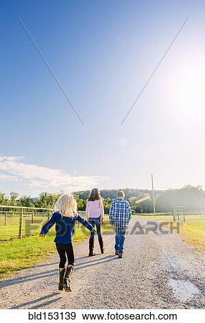 Stock Photo - Caucasian children walking on dirt road on ranch. Fotosearch