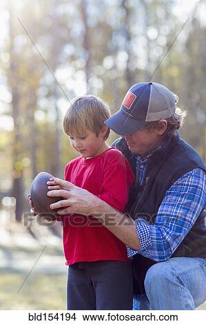 Picture - Caucasian father teaching son to play football. Fotosearch