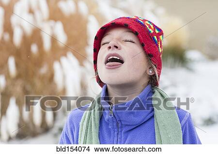 Picture - Caucasian girl catching snowflakes on tongue. Fotosearch
