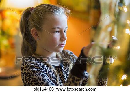 Caucasian girl decorating Christmas tree View Large Photo Image Stock Image - Caucasian girl decorating Christmas tree. Fotosearch