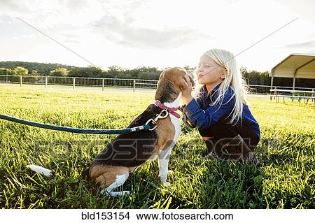 Picture - Caucasian girl kissing puppy on farm. Fotosearch